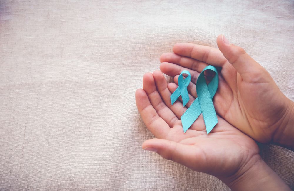 blue ribbon in hands for cervical cancer prevention week